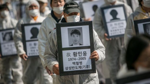 Biểu tình trước trụ sở của Samsung hôm 3/3: người biểu tình cầm theo di ảnh của 79 công nhân Samsung đã qua đời vì các căn bệnh mãn tĩnh, được cho là gây ra bởi các hóa chất tại nhà máy của Samsung.