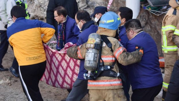 A handout photo made available by Kyongnamdomin Ilbo shows South Korean firefighters carrying a victim after a fire at a hospital in Miryang, South Korea, 26 January 2018