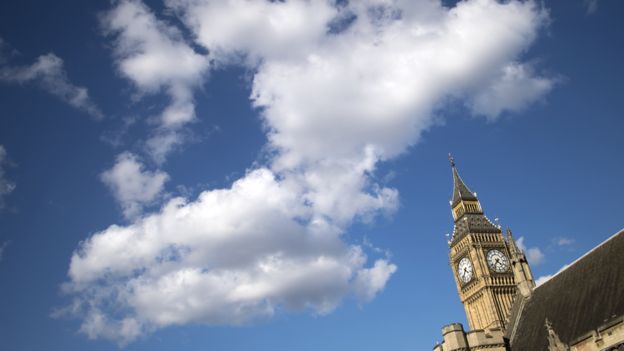 The very top of Big Ben seen against a backdrop of a blue sky with white clouds