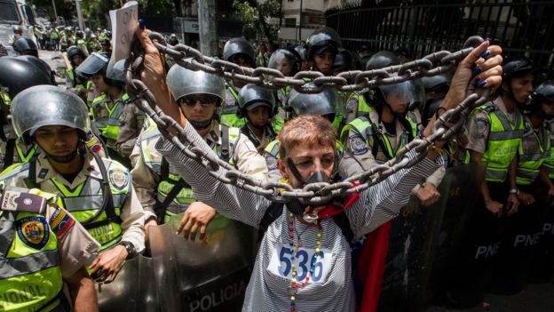 Mujer muestra cadenas frente a los policías.
