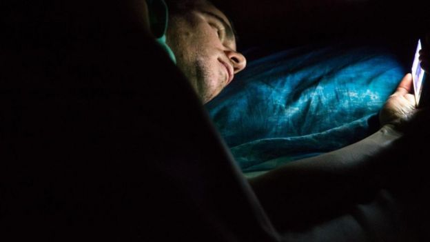 Homem com celular antes de dormir