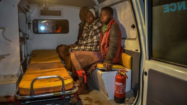 Local residents wait inside an ambulance after the Patel Dam burst