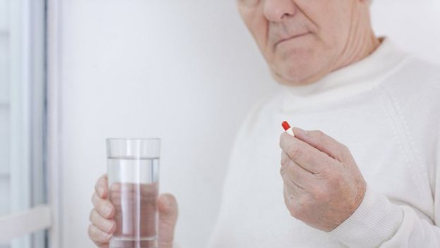 Elderly man taking pill