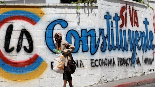 Una mujer camina frente a un grafitti en apoyo a la Constituyente de Venezuela