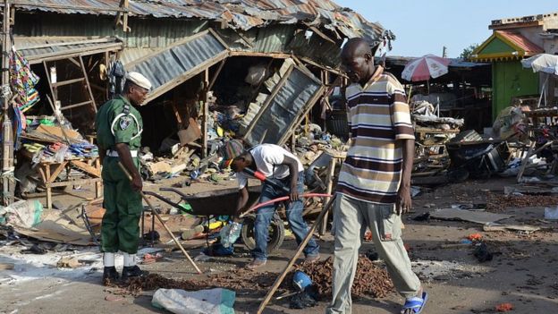 A man walks past a the scene of a bombing after at least 20 people were killed when a young female suicide bomber detonated her explosives at a bus station in Maiduguri, northeast Nigeria, on June 22, 2015 in an attack likely to be blamed on Boko Haram.