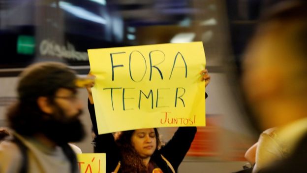 People hold a banner as they protest against Brazil's President Michel Temer in Sao Paulo, Brazil