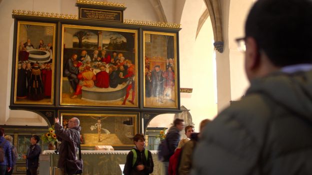 Martin Bashir stands looking at altarpiece picturing the Last Supper