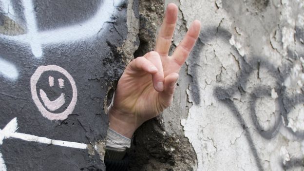 Señal de paz por ranura del muro de Berlín