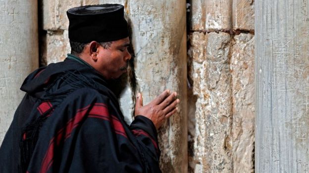 Un religioso orando en la puerta del Santo Sepulcro