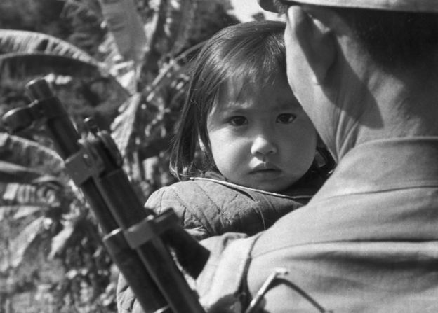 Niña cargada por soldado