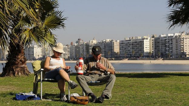 Dos personas toman mate en la rambla de Montevideo.