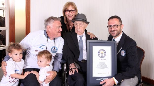 Marco Frigatti, of Guinness World Records, presenting Yisrael Kristal with his certificate of achievement for oldest living man, in the presence of the Kristal's daughter, her son and grandchildren.
