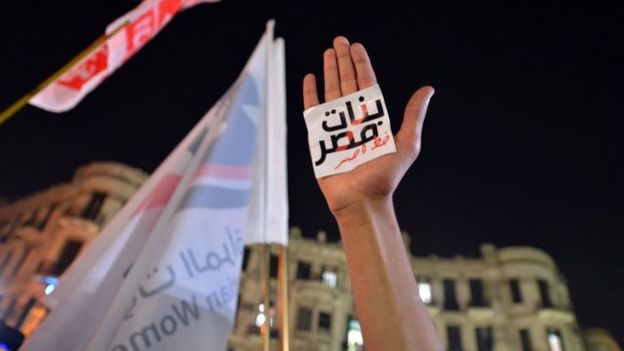 يد ولافتة مكتوب عليها "النساء خط أحمر"