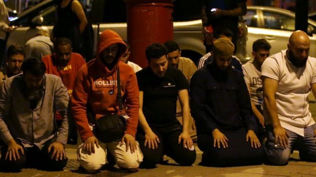 Worshippers pray on the street after the attack