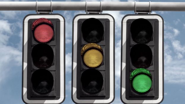 Tres semáforos alumbran en color rojo, amarillo y verde.