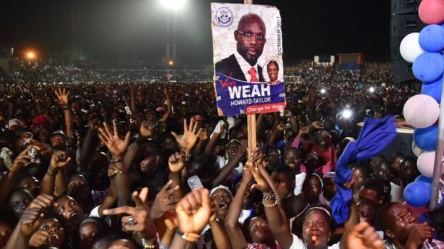 Supporters of former international Liberian football star turned politician George Weah wave during a presidential campaign rally in Monrovia on October 6, 2017