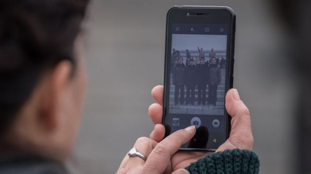 A woman takes a photo on her mobile phone in central Pyongyang