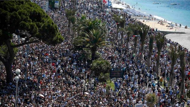 crowd gathering near a makeshift memorial on the Promenade des Anglais