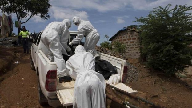 A burial team wearing protective clothing remove a body of a person suspected of having died of the Ebola virus in Freetown, Liberia (28 September 2014)