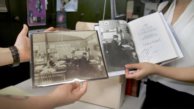 Bouquin, left, and Smith Zrull, right, hold up an original image of Williamina Fleming posing in the plate stacks in a 1891 photo that was the first photo used in bestselling author Dava Sobell's 2016 book, 