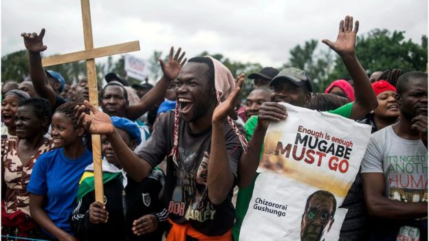 Protesters holding placards applaud and chant slogans at a rally in Harare to demand the resignation Robert Mugabe, 18 November.