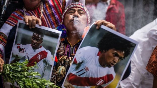 Un chamán con dos fotos de jugadores peruanos