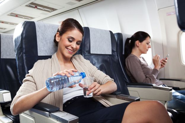 Mujer bebe agua durante un vuelo