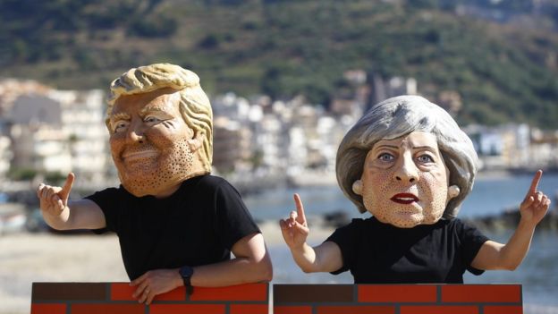 Manifestantes llevan máscaras de Theresa May y Donald Trump