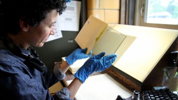 Curatorial assistant Anne Callahan inspects a plate before it is cleaned for scanning. She makes sure the metadata from the paper jacket is properly entered into the computer before the plate goes to be wiped down and then scanned.