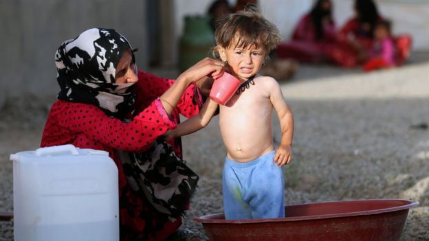 Woman bathes a child at al-Khazir camp between Mosul and Irbil - 27 May
