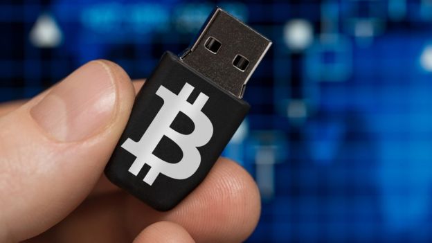 Hombre sosteniendo USB con el logo de bitcoin.
