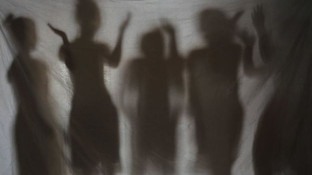 Sombras de mulheres atrás de um tecido