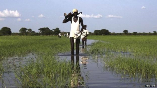 Raia wa Sudan kusini avuka mto akiwa amebeba bunduki