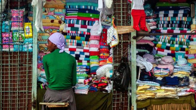 A vendor sits at a stall selling cloth towels, hats and other textiles in the Zimbabwean capital Harare on November 16, 2017