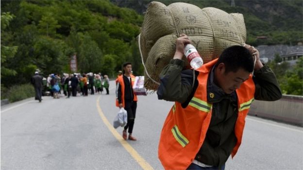 A man carries supplies as he heads to a landslide area in the village of Xinmo in Maoxian county, China's Sichuan province 25 June 2017