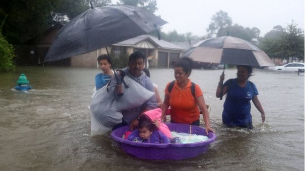People walk down a flooded street as they evacuate their homes after the area was inundated with flooding from Hurricane Harvey on 28 August 2017 in Houston, Texas