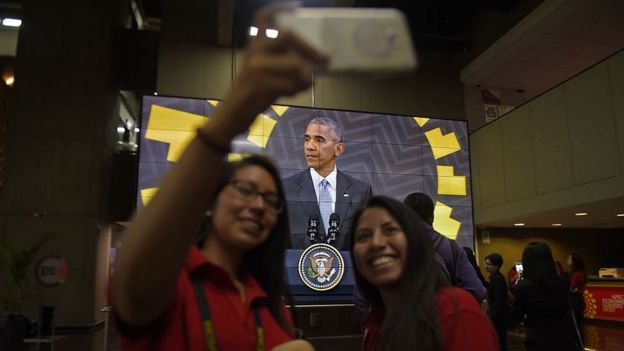 Chicas tomándose una selfie con Obama en el fondo, en Lima
