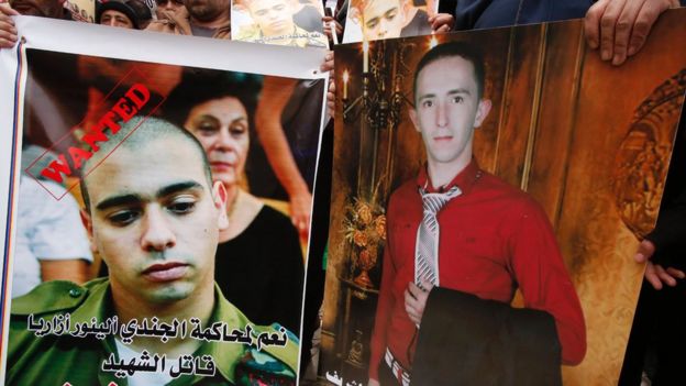 Palestinians hold posters as they gather in the street in the West Bank town of Hebron on January 4, 2017, during the trial of Israeli soldier Elor Azaria (portrat-L) who killed Abdul Fatah al-Sharif (portrait-R)