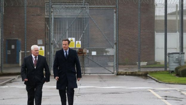 David Cameron is escorted by prison governor Stephen Ruddy (L) as he tours HMP Onley near Rugby
