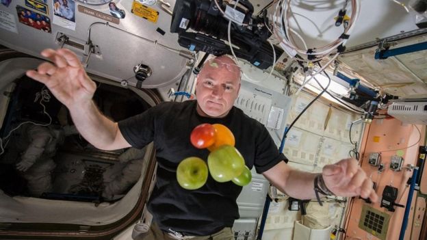 Un astronauta con frutas flotando frente a él