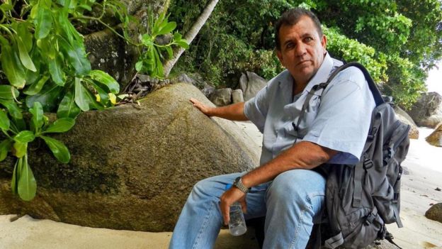 John sentado frente a una roca con unas marcas