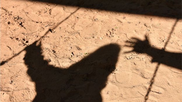 Sombra de una mano acercándose a la sombra de un niño.