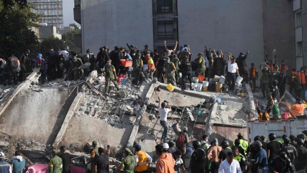 Rescuers and volunteers remove rubble and debris from a flattened building in search of survivors after a powerful quake in Mexico City on September 19, 2017.