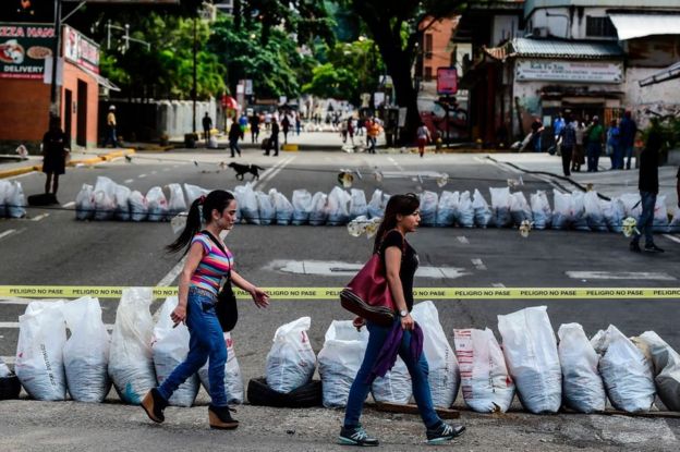Dos mujeres pasan frente una calle cortada en el barrio de Petare, en la capital de Venezuela, Caracas, el 26 de julio.