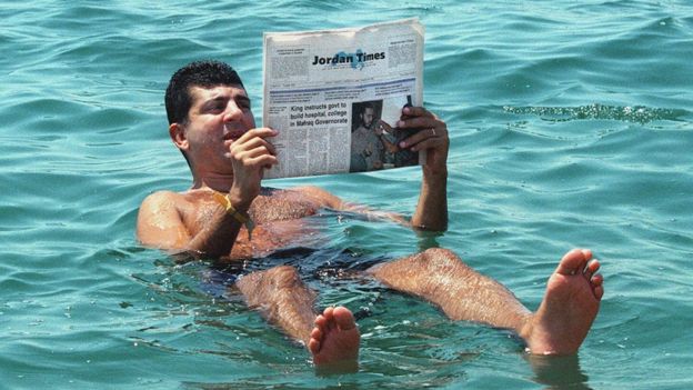 Un hombre lee el periódico mientras flota en el Mar Muerto el 31 de agosto de 1999