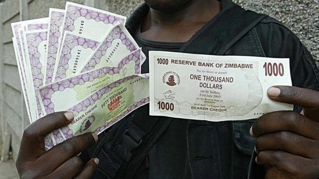 Harare resident holds up 1,000 and 50,000 dollar notes because of inflation, in 2006
