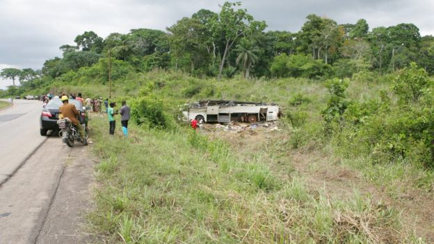 A vehicle involved in an accident lies on its in a wooded area along a highway in Cameroon.