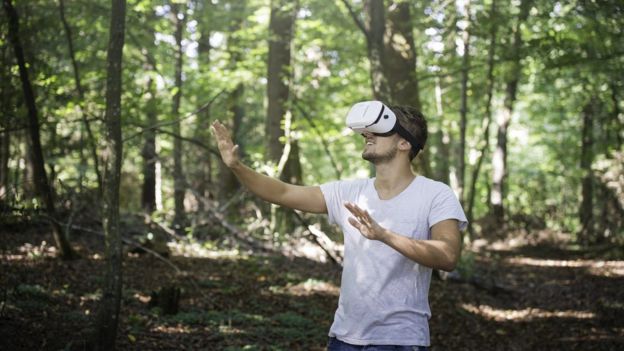 Un chico con unas gafas de realidad virtual en el bosque