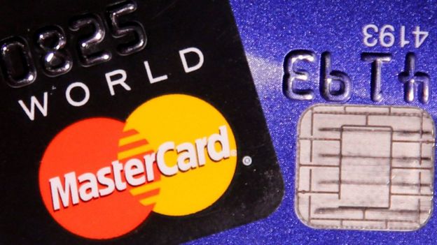Una tarjeta de crédito MasterCard se representa junto a un chip de computadora en una tarjeta bancaria