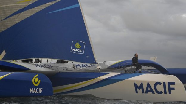 Francois Gabart is seen sitting on the hull of his trimaran Macif as it arrives back home in France